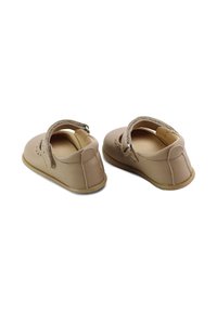 Zapatos de cuero marrón claro con punta redonda, correa en el tobillo y detalles perforados; suela plana y diseño simple y clásico.