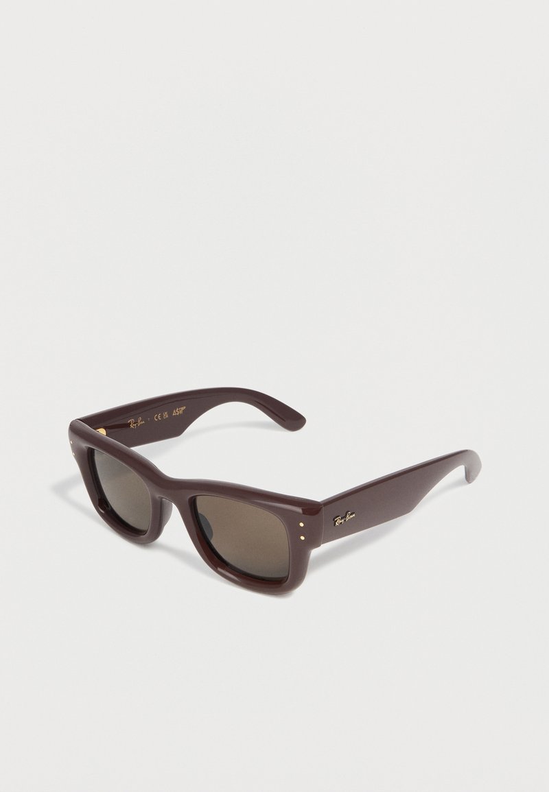 Καφέ ορθογώνια γυαλιά ηλίου Ray-Ban με χοντρές σκελετούς και σκοτεινούς φακούς, τοποθετημένα διαγωνίως σε λευκό φόντο.