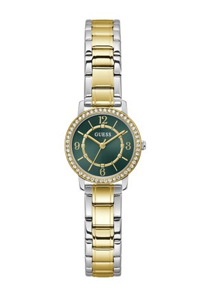 Montre-bracelet ronde en métal bicolore avec maillons dorés et argentés, cadran vert, chiffres dorés et lunette ornée de cristaux, nom de la marque "GUESS" sur le cadran.