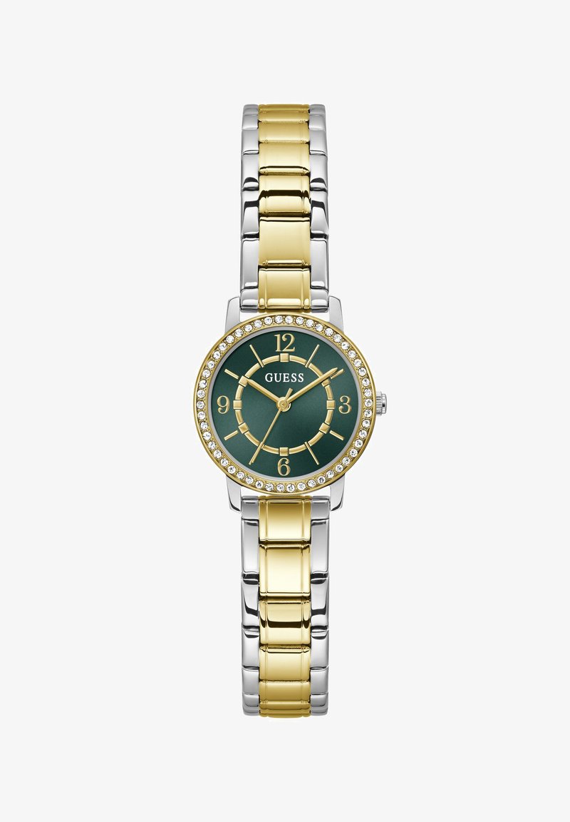 Montre-bracelet ronde en métal bicolore avec maillons dorés et argentés, cadran vert, chiffres dorés et lunette ornée de cristaux, nom de la marque "GUESS" sur le cadran.