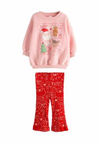 Roze sweatshirt met feestelijke graphics, gecombineerd met rode flared leggings met witte feestdagenpatronen, allemaal gemaakt van zachte materialen.