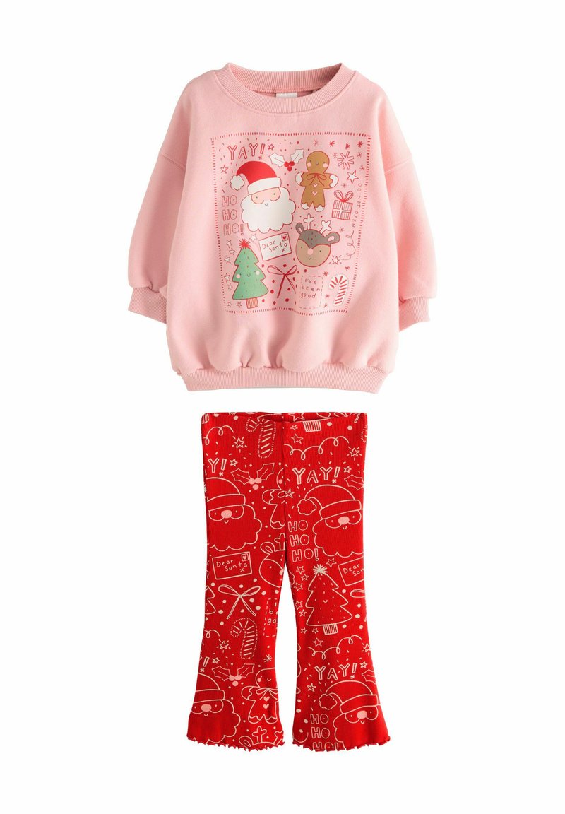 Roze sweatshirt met feestelijke graphics, gecombineerd met rode flared leggings met witte feestdagenpatronen, allemaal gemaakt van zachte materialen.