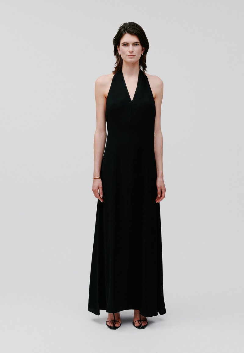 Black halter neck maxi dress with a sleek silhouette, made of smooth fabric. Features a deep V neckline and flows to the floor.
