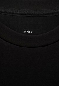 T-shirt in cotone nero con scollatura rotonda. L'etichetta "MNG" è stampata in bianco sul colletto. Tessuto morbido con una finitura liscia.