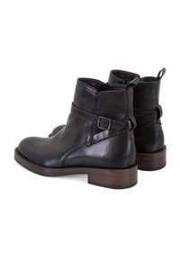 Dunkelbraune Leder-Stiefeletten mit glatter Textur, einem seitlichen Schnallenakzent und einem stabilen Holzabsatz. Entworfen für Langlebigkeit und Unterstützung.