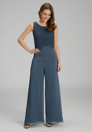 Salopette senza maniche con corpetto in pizzo di colore blu scuro, caratterizzata da pantaloni a gamba larga e una cintura liscia, arricchita da trame sottili.