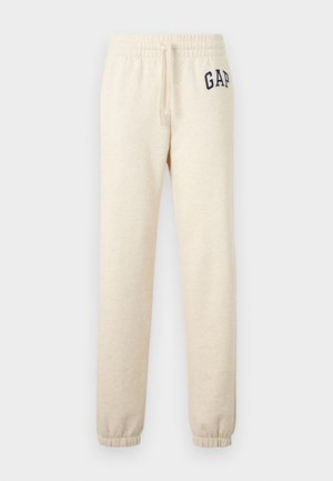 Béžové elastické tepláky s povrazcom a elastickými manžetami, s tmavomodrým logom "GAP" na hornej ľavej stehne.