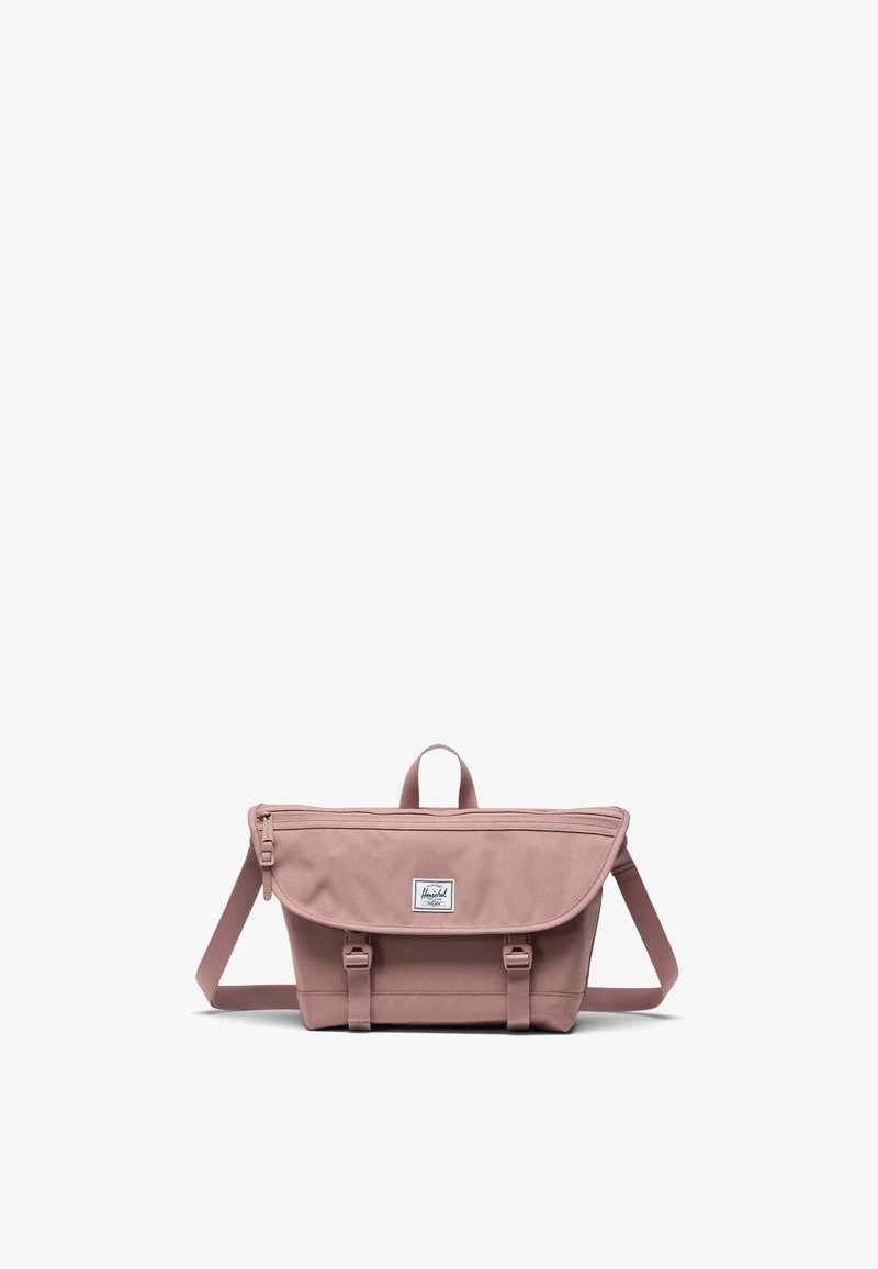 Ljusrosa canvas budväska med en vikbar klaff, handtag på toppen, justerbar axelrem och borstad silverfinish på detaljer.