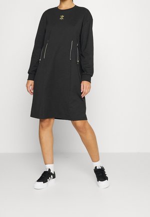 Svart långärmad klänning med rund halsringning, sidogömmor och guldblad broderi vid bröstet. Matchad med svart och vitt sneakers.