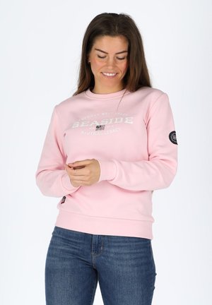 Lyserød sweatshirt lavet af blød bomuld, med en hvid trykt tekstdesign "SEASIDE" og et sort logo-patch på venstre ærme.