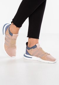 Scarpe sportive rosa e blu con tomaia in mesh, lacci elastici e pannelli testurizzati. Presentano una suola bianca con accenti blu e un anello posteriore.