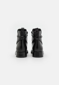 Black leather ankle boots with a smooth finish, featuring a side zipper and decorative straps across the back. Sturdy rubber sole.