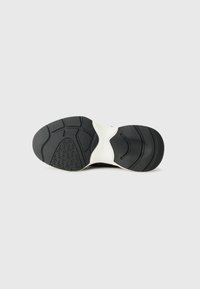 Suola di sneaker in bianco e nero con suola in gomma texturizzata, caratterizzata da linee curve e scanalature per trazione e supporto.