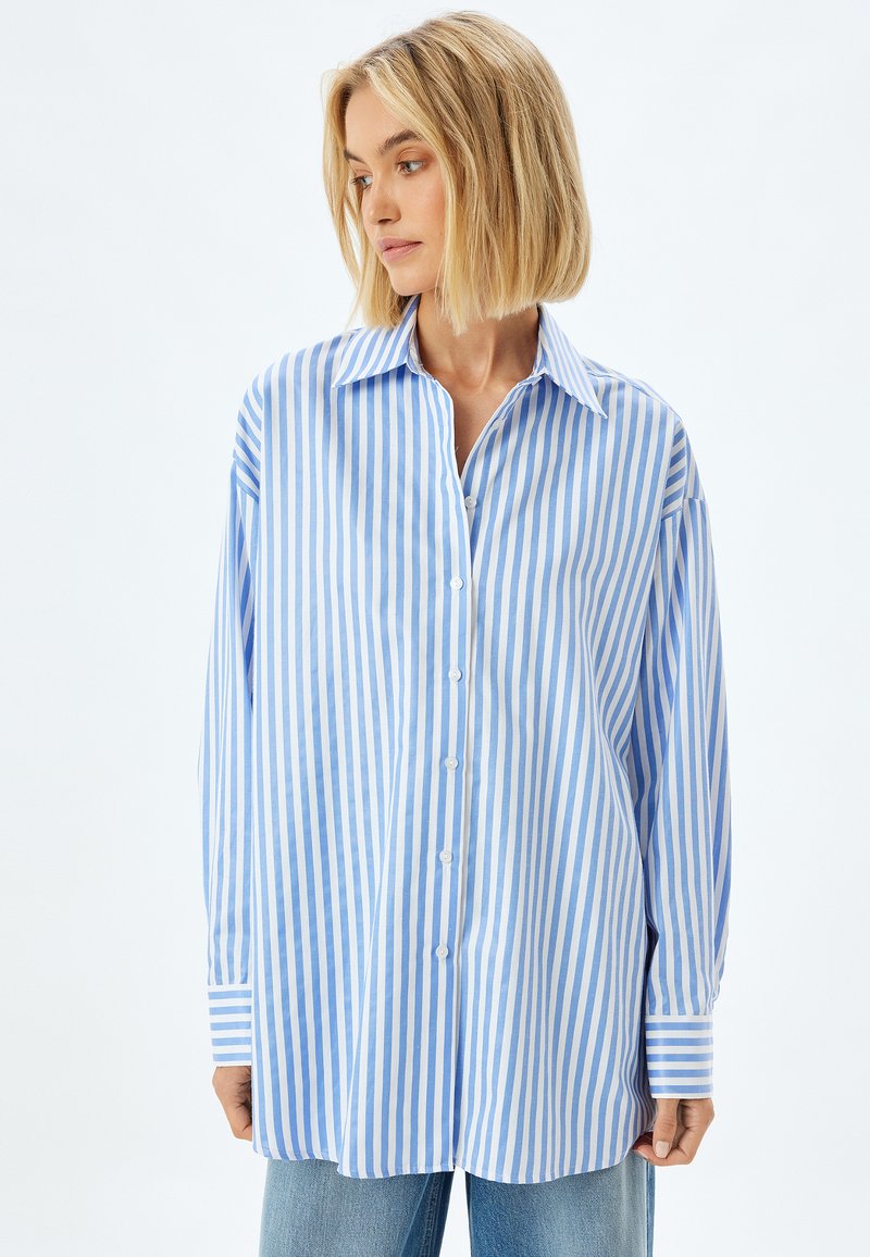 Blue and white striped oversized shirt, made of lightweight fabric, featuring a button-down front and wide cuffs.