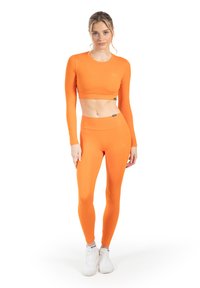 Oranje crop top met lange mouwen en bijpassende hoge taille legging gemaakt van rekbaar materiaal, met een aansluitend design en minimale branding.
