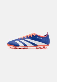 Botín de fútbol azul y blanco con parte superior sintética texturizada, acentos naranjas y cinco tacos moldeados para tracción. Presenta la marca "Predator".