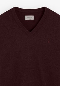 Burgundowy sweter w serek wykonany z miękkiego materiału, z prążkowanym kołnierzem i subtelnym haftowanym logo po lewej stronie.