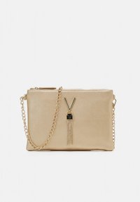 Pequena bolsa metálica dourada para usar ao ombro com alça de corrente, fecho de correr e pendente decorativo em forma de "V" na frente.