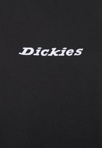 Svart t-shirt av bomull med vit broderad "Dickies"-logotyp. Har en mjuk textur och klassisk crew neck-design.