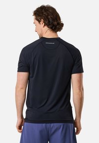 Zwarte sportieve shirt met korte mouwen en een ronde halslijn, voorzien van raglanmouwen en een subtiele logo op de rug. Gemaakt van lichtgewicht stof.
