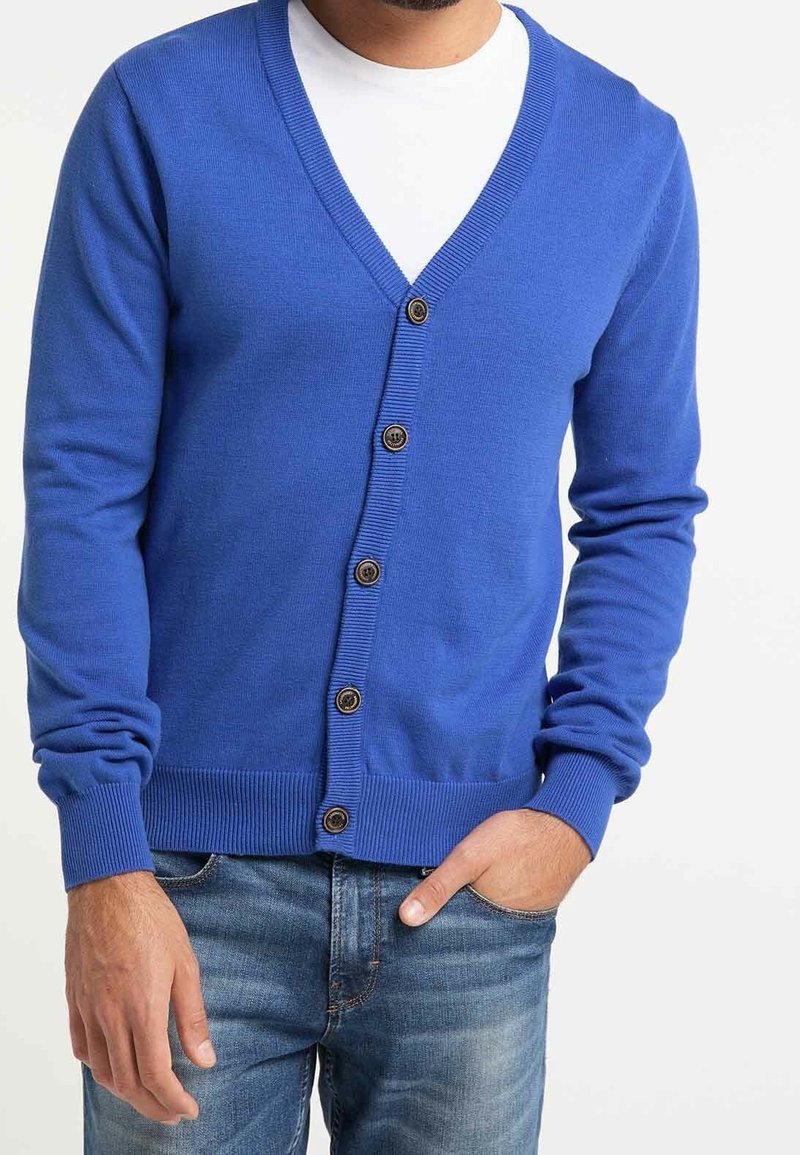 Blå stickad cardigan med djup V-ringning och sex bruna knappar framtill. Har ribbade ärmslut och midja, samt en mjuk textur.