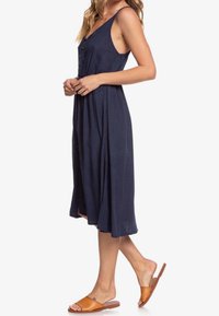 Námořnická modrá bezrukávová šaty vyrobené z lehkého materiálu, s knoflíkovou přední stranou, A-liniovým střihem, s volnou sukní a bočními rozparky.