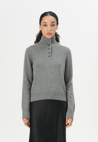 Pull en mélange de laine gris avec un col haut à côtes, une patte de boutonnage et un ourlet et des poignets côtelés. Texture lisse, silhouette ajustée.