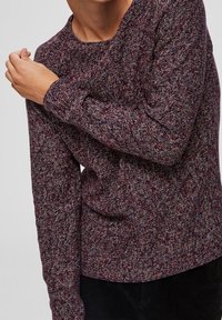 Pletený svetr v burgundské a šedé melírované vzoru. Má dlouhé rukávy a kulatý výstřih, vyrobený z měkké, texturované látky.