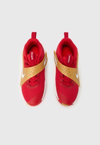 Κόκκινα αθλητικά παπούτσια με χρυσές λεπτομέρειες, διαθέτουν υφασμένο επάνω μέρος, επενδεδυμένο κολάρο και φαρδιά λουράκι στον αστράγαλο με λευκό λογότυπο Nike.