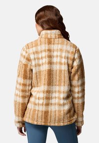 Tan and white plaid fleece jacket with a high collar and soft, textured fabric. Features a relaxed fit and rounded hem.
