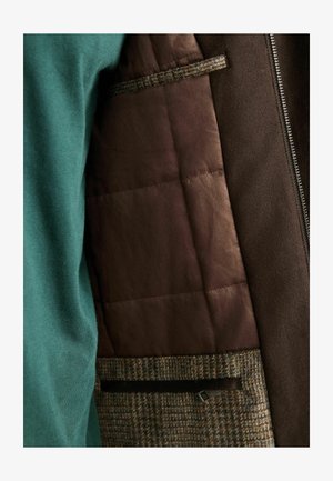 Roheline sviiter ja pruun jakki, millel on tikitud pruun vooder. Omab tekstureeritud villakangast mustrit ja tõmblukku; sisaldab tasku detaili.