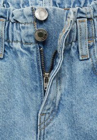 Helleblaue Jeans aus Denim mit gerafftem Bund, metallenen Knopfverschluss und Reißverschluss, sichtbaren Nähten und strukturellen Details.