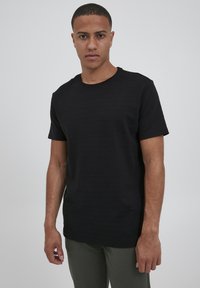 Svart kortermet t-skjorte med en teksturert stripe mønster, rund hals, og regular fit, brukt sammen med olivengrønne bukser.