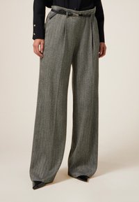 Pantaloni grigi a motivo pied de poule con gamba larga, frontale plissettato e cintura nera. Realizzati in tessuto testurizzato, presentano una vestibilità sartoriale e pieghe nette.