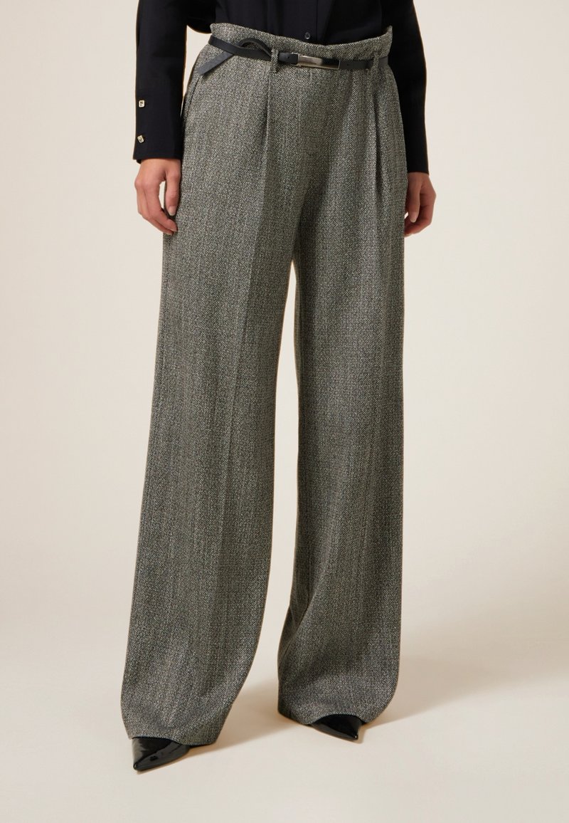 Pantaloni grigi a motivo pied de poule con gamba larga, frontale plissettato e cintura nera. Realizzati in tessuto testurizzato, presentano una vestibilità sartoriale e pieghe nette.
