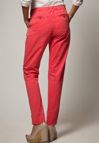 Röda bomullsbyxor har en rak ben-design med två bakfickor och subtila sömnadsdetaljer, kombinerat med beige klackar och korkdetaljer.