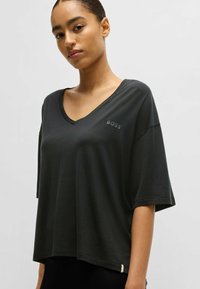 Black V-neck t-shirt with loose fit, short sleeves, and subtle "BOSS" logo on chest; smooth texture and slightly oversized design.