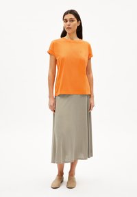 T-shirt arancione a maniche corte con risvolti, abbinato a una lunga gonna grigia chiara. Tessuto morbido, vestibilità comoda e design semplice.