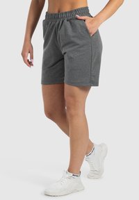Grijze katoenen shorts met een elastische tailleband, zijzakken en een losse pasvorm. Gecombineerd met witte sportieve schoenen voor een casual look.