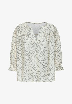 Balta blūze ar mazu zilu ziedu rakstu, V-veida kaklu un savērtām pūkainām piedurknēm. Izgatavota no viegla auduma ar mīkstu tekstūru.