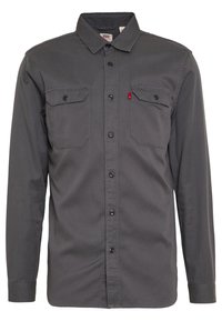 Grå långärmad skjorta i en bomullsblandning, med spetsig krage, två bröstfickor, knäppning framtill och svarta knappar.