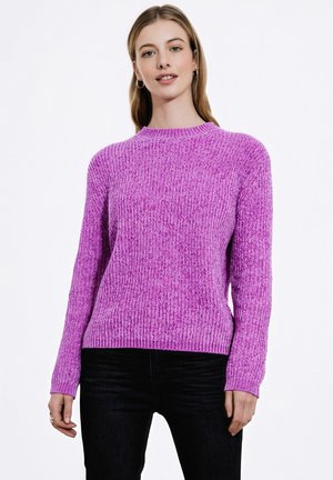 Fioletowy sweter z ribstopu, z długimi rękawami i okrągłym dekoltem, o teksturowanym wykończeniu. Zestawiony z czarnymi dżinsami.