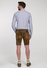 Bruna lädershorts, ljusblå skjorta med knappar, jordnära färger, knälånga, texturerat läder, avslappnat fotriktiga med stickade strumpor.