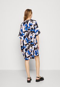 Un vestido holgado, de longitud hasta la rodilla, hecho de tela ligera en patrones abstractos de color rosa, azul y negro, con mangas cortas y un cuello redondo.