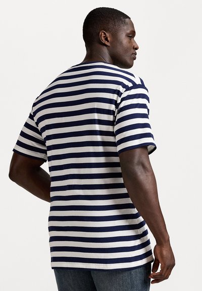 Īsām piedurknēm T-kreklis ar tumši zilu un baltu horizontālo svītru rakstu, kokvilnas audums, brīvs piegriezums, apaļa kakla izgriezuma forma un taisna apakšmala.