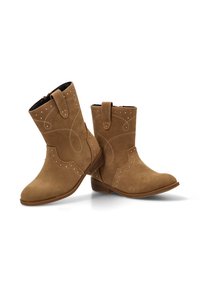 Botines de ante en tono marrón claro con punta redondeada, costuras decorativas, acentos de tachuelas y lengüetas laterales para una fácil colocación.