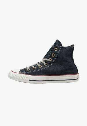 Hoge sneakers van donkerdenim met een witte rubberen zool, voorzien van gouden vetertjes, beige veters en rode accenten langs de zool.