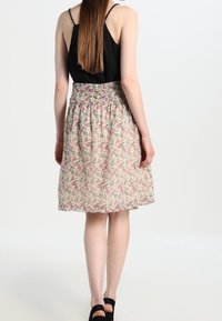 Falda floral con una base de color beige claro, que presenta patrones florales en tonos rosa y verde. Cintura elástica y diseño hasta la rodilla.