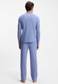 Lichtblauw tweedelig lounge-set gemaakt van gestructureerde stof, met lange mouwen en broek met rechte pijpen, in een ontspannen pasvorm.
