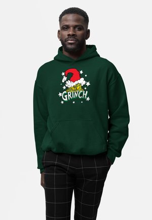 Groene hoodie met een Grinch-afbeelding met een rode kerstmanmuts en witte accenten. Pullovermodel met een buidelzak, gestructureerde stof.